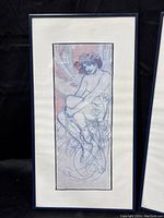 Front view of first framed artwork showing seated female figure with floral elements and pinkish background.