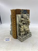 Side view of one marble floral carved bookend with antique book between the pair