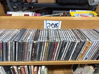 Front view of a wooden shelf with approximately 20 rock, pop, and jazz music CDs lined up.