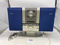 Front view of Fisher stereo system showing the CD compartment, control panel, digital display, and the two blue-covered speakers.