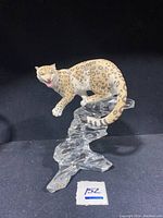 Front left angled view of snow leopard figurine mounted on clear textured base.