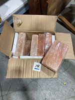 Open box showing 10 individually wrapped Himalayan salt blocks, pinkish color, size approximately 2x4x8 inches, arranged inside a cardboard box.