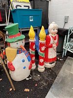 Full group of four holiday blow molds on display including snowman, Mrs. Claus, and two candles.