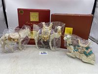 Three wrapped porcelain animal figurines with red Lenox boxes in background