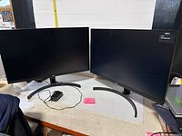 Two LG 27" monitors side by side on table with one power adapter visible