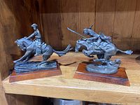 Both sculptures side by side on wooden shelf