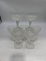 Front view of 7 Waterford crystal wine/champagne glasses grouped together showing decorative cut patterns on bowls.