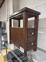 Side view showing the two small drawers with metal handles and the solid back panel of the wooden end table.