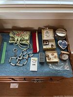 Wide shot of all items showing jewelry roll, pearl necklaces, brooches, trinket dishes, clock, and jewelry boxes