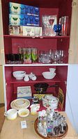 Overall view of upper and lower shelves with more kitchen items: white bowls, cast iron pan, floral baking dish, plates, and assorted kitchenware