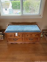 Front view of Huppe cedar chest with blue padded seat showing all drawers and scalloped bottom trim.