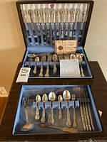 Full view of the Oneida Community Affection silver plate cutlery set inside wooden velvet-lined storage box, showing knives, forks, spoons, and serving utensils organized in compartments.