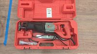 Electric Milwaukee reciprocating saw with power cord and two Milwaukee branded saw blades in red molded plastic carrying case