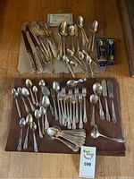 Full overview of the cutlery laid out on a table showing multiple forks, knives, spoons, and serving pieces.