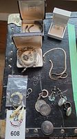 Overview of sterling silver jewelry lot on black surface showing bracelets, necklaces, earrings, and rings including storage boxes and bag with tag.