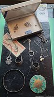 Full lot showing all jewelry items on black surface and the original box containing two pins.