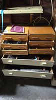 Wooden drawers with multiple compartments containing assorted hand tools including saws and screwdrivers.