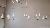 Full view of the vintage sailboat mobile hanging from a light fixture showcasing all the suspended sailboats.