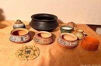 Full lot view showing all pottery pieces arranged on a wooden surface including painted small pots and miniature pottery