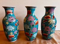 Photo showing 3 Chinese porcelain vases, turquoise with multicolor hand-painted flowers and glazed finish.