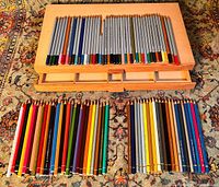 Top view of the wooden pencil box with pencils laid out showing three groups of pencils in different brands and colors