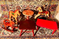 Overall set showing three toy rocking horses and three wooden tables on patterned carpet