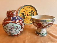 Overall view of the three-piece vintage Chinese porcelain set, showing ginger jar, footed bowl, and plate with dragon designs