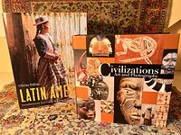 Photo showing two books with their covers visible: 'Latin America' with an image of a traditionally dressed person and 'Civilizations: Art and Photography' featuring tribal art images.