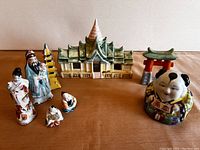 All porcelain miniature figurines displayed on a flat surface showing human figurines and architectural models with variety of colors and details