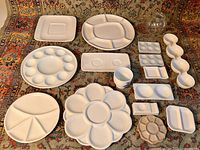 Top view of all porcelain mixing trays spread out on a patterned rug showing variety of sizes and shapes