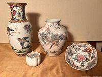 Photo showing the full set of four items on display: two decorated vases, the hexagonal bowl, and the white lotus flower frog.