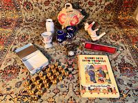 Full lot overview showing clay whistles, brass goblets, Mexican piggy bank, miniature vases, telephone, stained glass kaleidoscope, and children's book