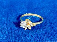 Front view of ring on blue background showing central round CZ and two side stones