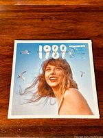 Front cover image showing Taylor Swift smiling against a blue sky with seagulls, labeled '1989 Taylor's Version'.