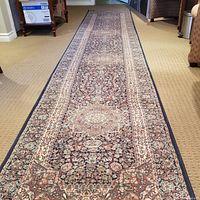 Full length view of the 13 ft navy hall runner carpet laid out on a carpeted floor, showing the intricate floral and medallion pattern with navy blue borders.