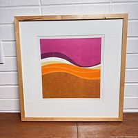 Frontal photo of framed abstract art print showing wood frame and colored wavy bands.