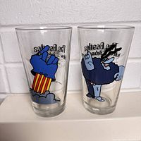 Front view of two pint glasses showing colorful Beatles Yellow Submarine characters and partial text.