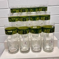 Twelve Grolsch 400 Year Anniversary beer glasses arranged in three rows of four glasses, displaying the green decorative band and embossed Grolsch logo.
