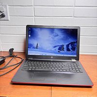 Front view of the HP 15-inch laptop powered on showing the screen and keyboard.