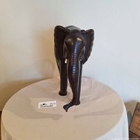 Front view of dark brown ironwood elephant carving showing broken tusks.