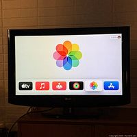 Front view of LG TV powered on showing app selection screen with color wheel icon