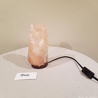 Rock salt table lamp shown unlit on a round table with visible power cord and inline switch