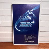 Framed Starlight Express original London production musical poster on a wooden surface against a light brick wall.