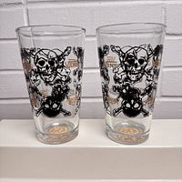 Two Vans bar glasses with skull and crossbones design displayed side by side on a white surface showing front of glasses.