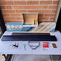 Full view of Bond knitting machine bed, tools, accessories, and original box laid out on table.