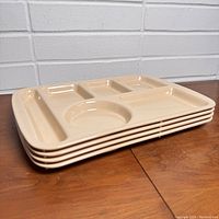 Stack of 4 beige vintage cafeteria lunch trays showing thickness and shape