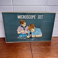 Closed box showing vintage illustrated packaging with two boys using microscope set