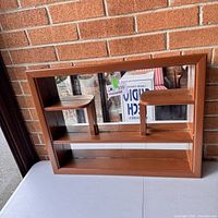 Front view of vintage wooden curio shelf showing mirror back and dual raised small shelves.