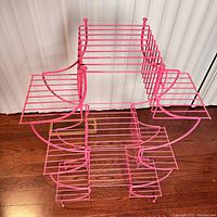 Front angle view of the pink pagoda style wire plant stand showing multiple open shelving tiers and overall structure.