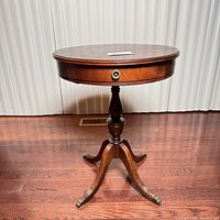 Front view of the round wood hall table showing the drawer and pedestal base with claw feet.